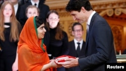 Le Premier ministre canadien Justin Trudeau offrant le drapeau canadien à Malala Yousafzai à la librairie du Parlement, à Ottawa, le 12 avril 2017.