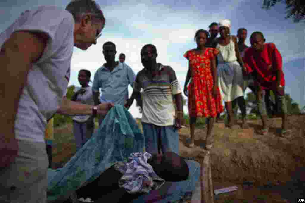 People watch a US missionary doctor confirm the man lying in the bed died of cholera outside a hospital in the town of Droin, Haiti, Friday Oct. 22, 2010. An outbreak of cholera in rural central Haiti has killed at least 142 people and sickened hundreds