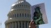 FILE - An activist holds up a pro-refugee image during a demonstration outside the U.S. Capitol in Washington, Oct. 15, 2019.