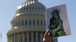 FILE - An activist holds up a pro-refugee image during a demonstration outside of the U.S. Capitol in Washington, Oct. 15, 2019.