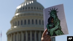 FILE - An activist holds up a pro-refugee image during a demonstration outside of the U.S. Capitol in Washington, Oct. 15, 2019.