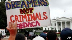 FILE - A woman holds up a signs in support of Deferred Action for Childhood Arrivals, or DACA, during an immigration reform rally at the White House in Washington, Aug. 15, 2017.