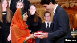 Canada's Prime Minister Justin Trudeau (R) presents Pakistani Nobel Peace Prize laureate Malala Yousafzai with a Canadian flag during a ceremony in the Library of Parliament on Parliament Hill in Ottawa, Ontario, Canada, April 12, 2017. Yousafzai also became an honorary Canadian citizen.