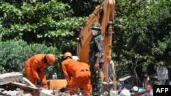 Nhân viên cứu hộ tìm kiếm nạn nhân trong nhà cửa đổ sập sau trận động đất trên đảo Lombok, Indonesia.