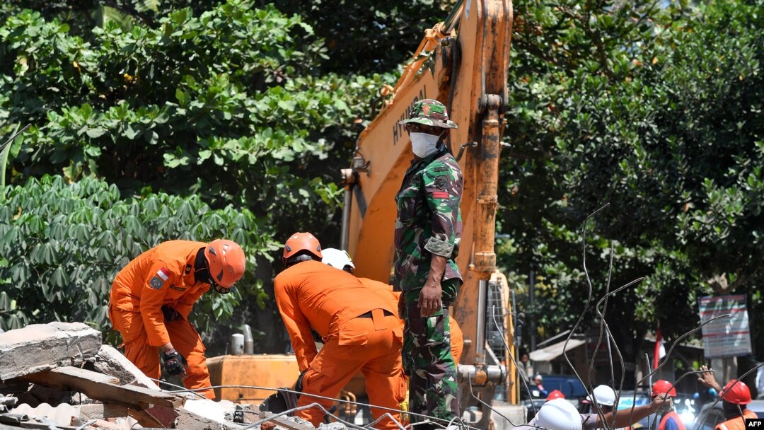 Nhân viên cứu hộ tìm kiếm nạn nhân trong nhà cửa đổ sập sau trận động đất trên đảo Lombok, Indonesia.