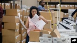 A Broward County Supervisor of Elections worker looks at a ballot during a canvasing board meeting, Nov. 9, 2018, in Lauderhill, Fla. 