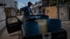 Seorang pria di Veracruz, Meksiko, tampak mengisi air ke sejumlah bak besar di tengah krisis air yang melanda wilayah tersebut pada 16 Juni 2024. (Foto: AP/Felix Marquez)