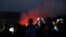 Visitors take pictures as Kilauea's summit crater glows red in Volcanoes National Park, Hawaii, May 9, 2018. Geologists warned Wednesday that Hawaii's Kilauea volcano could erupt explosively and send boulders, rocks and ash into the air around its summit in the coming weeks. 