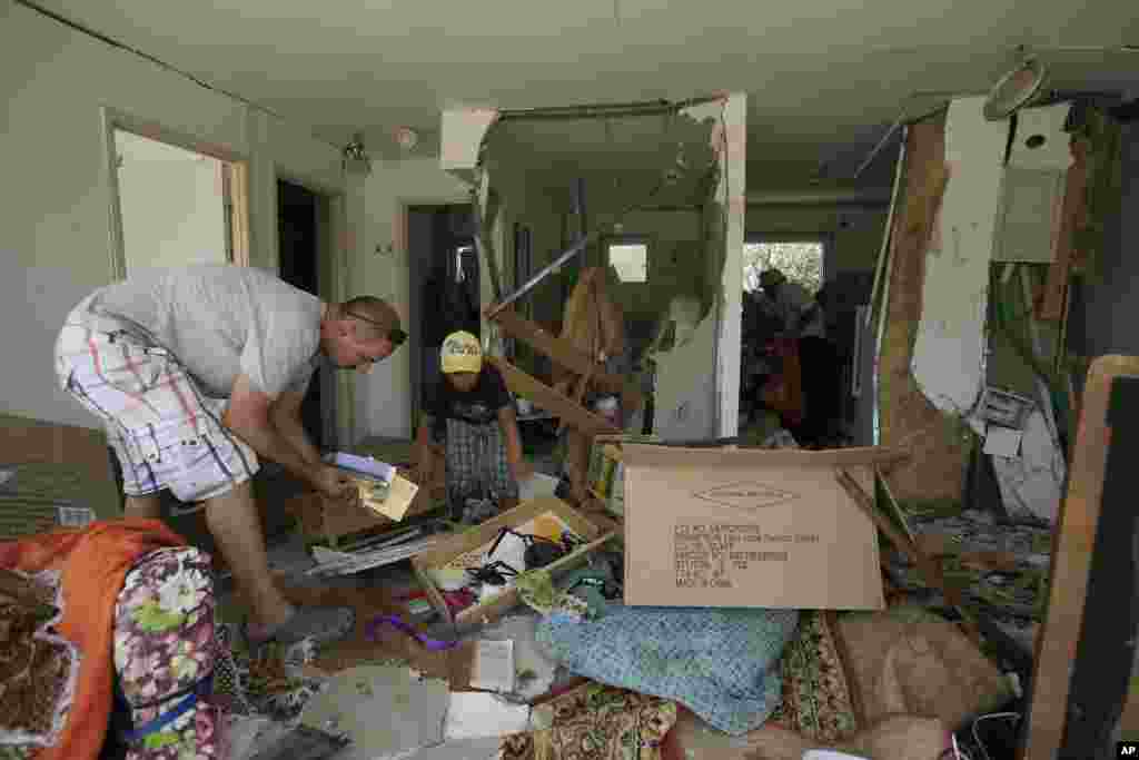 Israelis salvage belongings from a house of their relative after it was hit by a rocket fired from the Gaza Strip Saturday in the southern city of Beersheba, Israel, July 12, 2014.