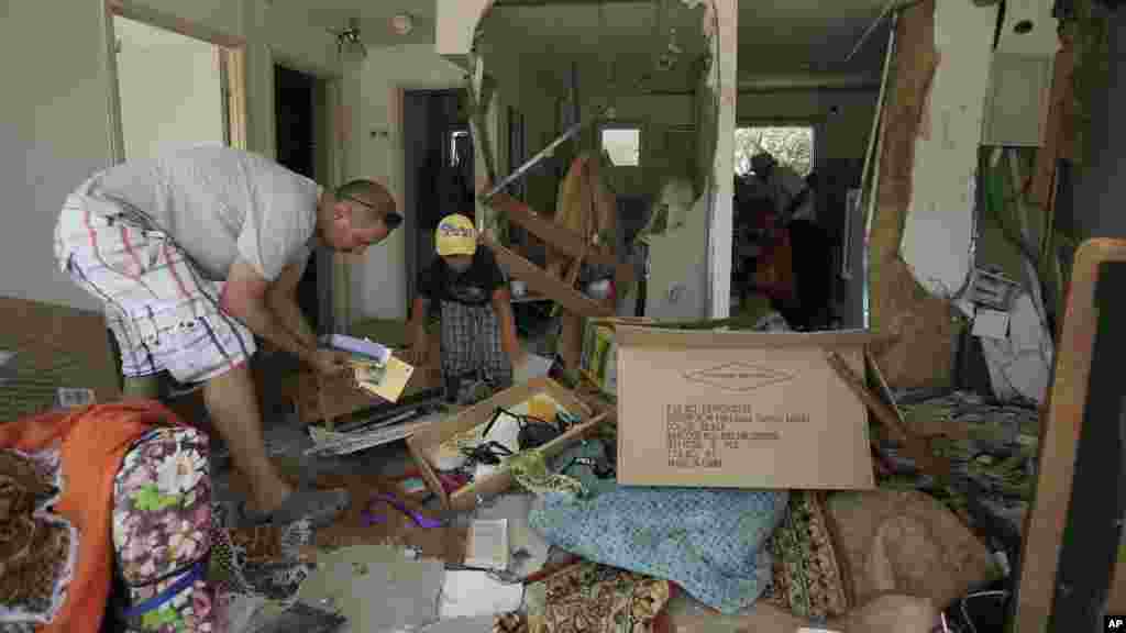 Israelis salvage belongings from a house of their relative after it was hit by a rocket fired from the Gaza Strip Saturday in the southern city of Beersheba, Israel, July 12, 2014.