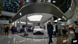 FILE - People walk through a floor section selling various Chinese-made electric car brands inside a shopping mall in Beijing on Jan. 9, 2024. The U.S. announced on Feb. 29, 2024, an investigation into threats by connected vehicles from countries such as China.