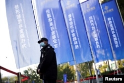 FILE - A security guard stands outside the venue of the Financial Street Forum annual conference in Beijing, China, Oct. 20, 2021.