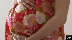 A woman holds her stomach during the last stages of her pregnancy in Bordeaux, France, April 28, 2010.