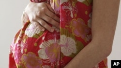 A woman holds her stomach during the last stages of her pregnancy in Bordeaux, France, April 28, 2010.