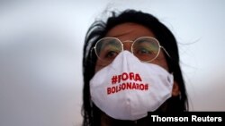 An artist wearing a protective mask reading "Out Bolsonaro" attends a protest to honour people who died from the coronavirus disease (COVID-19) during its outbreak in Brasilia, Brazil June 15, 2020.
