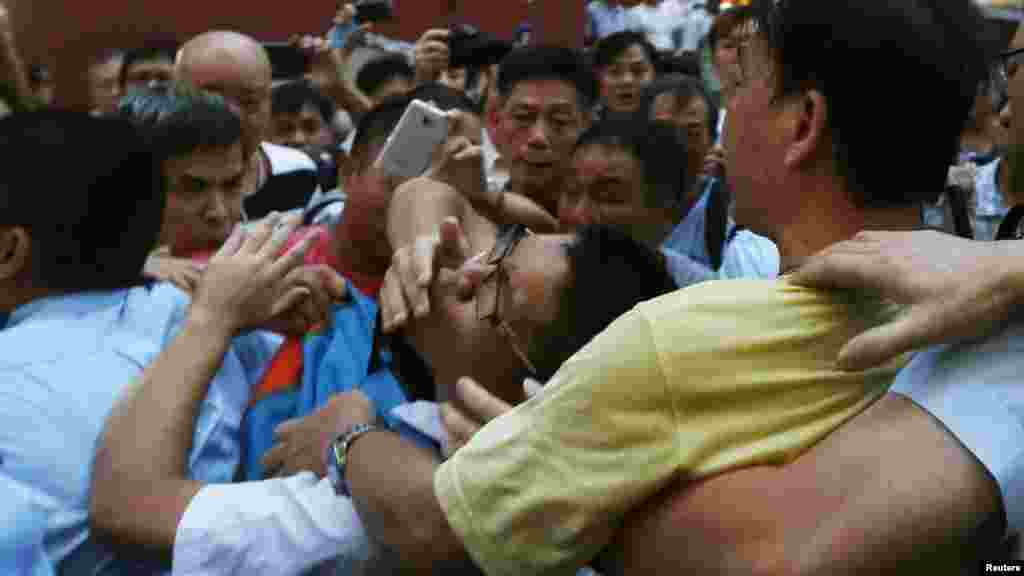 A pro-democracy protester, center, is grabbed by an anti-Occupy Central protester, right, at Hong Kong's shopping Mongkok district, where a main road is occupied, Oct. 3, 2014. 