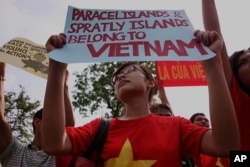 FILE - Protesters hold up Vietnamese flags and anti-China banners in front of the Chinese embassy during a protest against the alleged invasion of Vietnamese territory by Chinese ships in disputed waters in Hanoi, June 12, 2011.