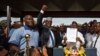 FILE - opposition politician Miguna Miguna, center, raises his fist as a gesture to the crowd as he stands next to opposition leader Raila Odinga, center-right, and politician James Orengo, far right, as Odinga holds an oath during a mock "swearing-in" ceremony at Uhuru Park in downtown Nairobi, Kenya, Jan. 30, 2018. 