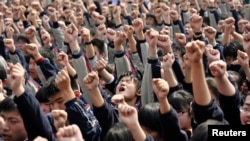 FILE - Students yell slogans such as "I must go to college" and "Father and mother, I love you" following the instructions of a lecturer during a speech at a high school in Nanjing, Jiangsu province, March 28, 2012. The speech aims to boost the morale of students before they sit for their National College Entrance Exams, local media reported. 