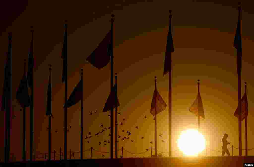 A woman walks during sunrise at the National Mall in Washington.