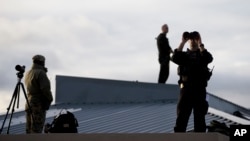 Agentes del Servicio Secreto montan guardia desde el techo de un edificio.