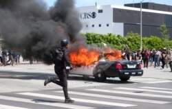 Una persona corre mientras un vehículo de la policía arde durante una protesta por la muerte de George Floyd. Los Angeles, mayo 30 de 2020.