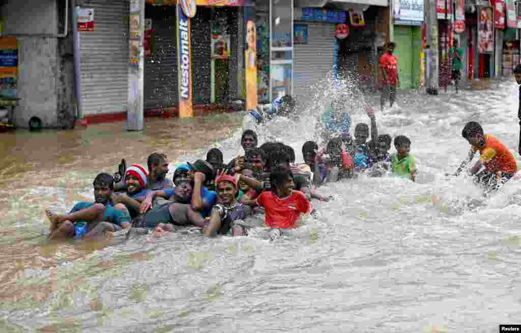 People play on a flooded road after they moved out of their houses in Biyagama, Sri Lanka.