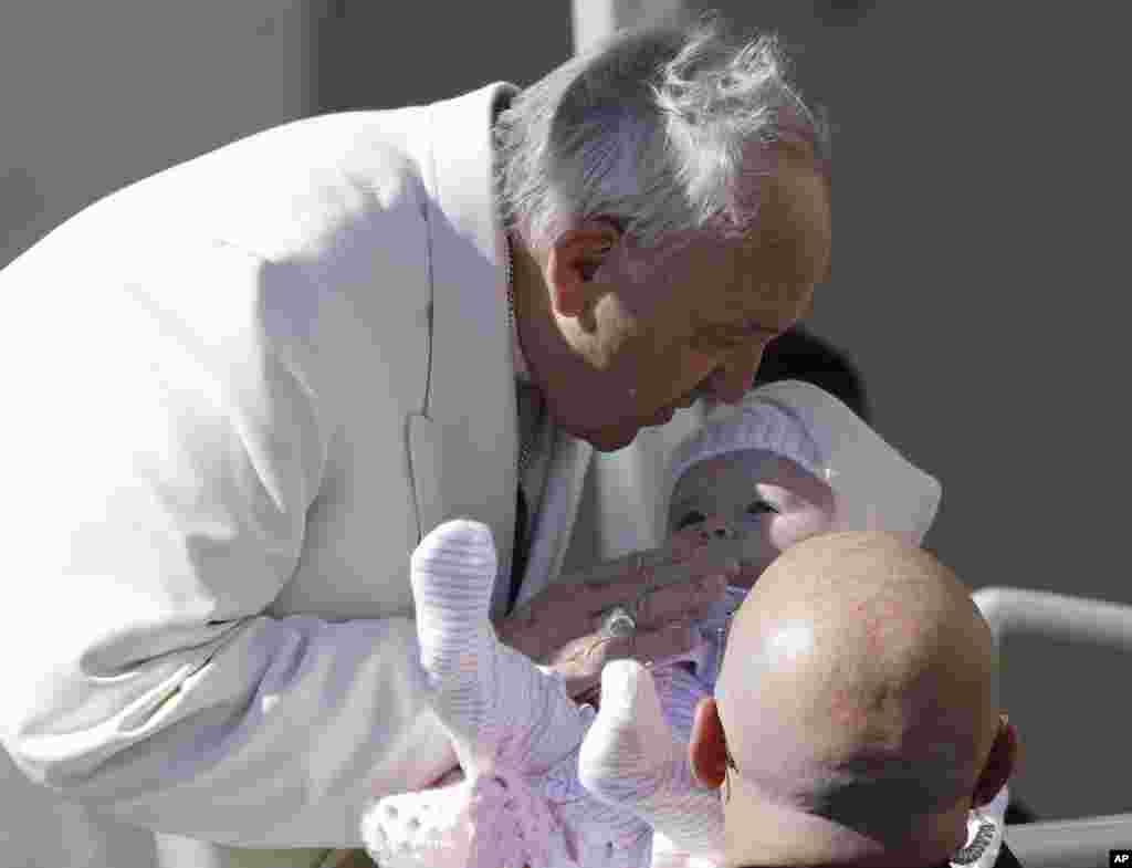 پاپ فرانسیس، رهبرکاتوبیک های جهان پیش از سخنرانی هفتگی خود در میدان سنت پیترز واتیکان، کودکی را متبرک می کند.