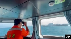 Seorang anggota Garda Pantai Taiwan memantau kapal Garda Pantai China saat melintas di dekat pantai Kepulauan Matsu, Taiwan, 14 Oktober 2024. (via AP)