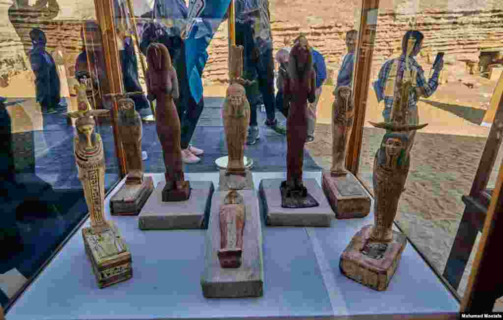 Wood statues of god Ptah-Sokar-Osiris, several of which bear hieroglyphic inscriptions. The statues show an anthropomorphic god standing on a wooden base and wearing a tall crown with two large feathers. (H. Elrasam/VOA) 