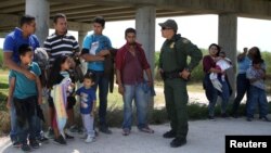 FILE - Border patrol agent Sergio Ramirez talks with migrants who illegally crossed the border from Mexico into the U.S., in the Rio Grande Valley sector, near McAllen, Texas, April 2, 2018.