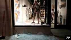 Scott McRoberts helps clean up broken glass after a violent crowd broke windows of many businesses after clashing with police, Sept. 16, 2017, in University City, Mo. Earlier, protesters marched peacefully in response to a not guilty verdict in the trial of former St. Louis police officer Jason Stockley. 