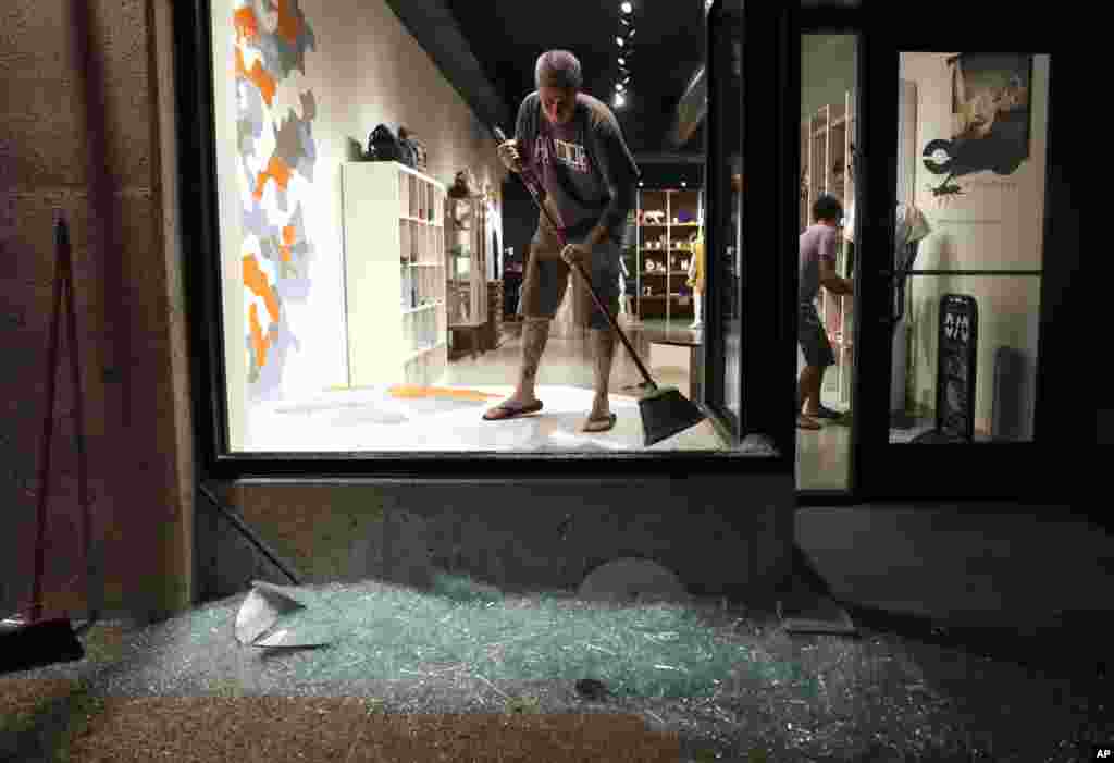 Scott McRoberts helps clean up broken glass after a violent crowd broke windows of many businesses after clashing with police, Sept. 16, 2017, in University City, Missouri. Earlier, protesters marched peacefully in response to a not guilty verdict in the trial of former St. Louis police officer Jason Stockley.