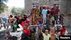 Children play on an abandoned car near a protest, which is against the dissolution of Yemen's parliament and the Shi'ite Muslim Houthi militia's tightening grip on power, in the southwestern city of Taiz, Feb. 13, 2015. 