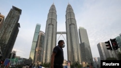 Seorang pria melintasi jalan di depan Menara Kembar Petronas, di tengah wabah COVID-19 di Kuala Lumpur, Malaysia 11 Agustus 2020. (Foto: REUTERS/Lim Huey Teng)