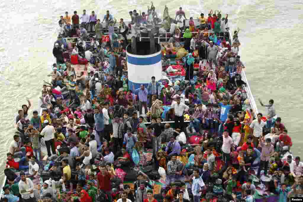 People look on from an overcrowded passenger boat navigating through the Buriganga River in Dhaka, Bangladesh.