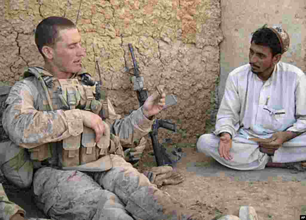 2010年9月26日，美国海军陆战队中士本森(左)向阿富汗当地百姓提问时举起一颗战场上留下的子弹壳。