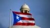 FILE - A Puerto Rican national flag flies in front of the Capitol building in San Juan, Puerto Rico, July 29, 2015. The island’s two biggest political parties hold gubernatorial primaries on Sunday, June 2, 2024.