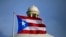 FILE - A Puerto Rican national flag flies in front of the Capitol building in San Juan, Puerto Rico, July 29, 2015. The island’s two biggest political parties hold gubernatorial primaries on Sunday, June 2, 2024.