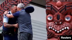 Seorang petugas polisi dan seorang pria melakukan ritual Hongi setelah upacara "Karakia", yang dihadiri perwakilan Ngati Awa dan kerabat korban letusan gunung berapi, di rumah Mataatua Marae, Whakatane, Selandia Baru, 12 Desember 2019. 