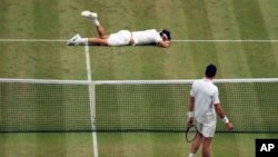 Roger Federer de Suisse, en haut, tombe au cours de son match en demi-finale de simple messieurs contre Milos Raonic du Canada au douzième jour du Championnat de Wimbledon à Londres, 8 juillet 2016.