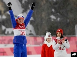 Gold medal winner Maren Lundby, of Norway, celebrates as bronze medal winner Sara Takanashi, of Japan, looks on during the Venue Ceremony for the women's normal hill individual ski jumping competition at the 2018 Winter Olympics in Pyeongchang