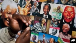 A well-wisher uses his phone to take a picture of a banner of photos of Nelson Mandela, outside the Mediclinic Heart Hospital in Pretoria, July 18, 2013. 