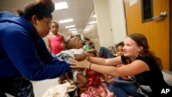 Mokeyonia Bell lleva a su hija de 2 meses a un refugio de evacuación establecido en la Escuela Secundaria Rutherford, antes del huracán Michael toque tierra en Panama City Beach, Florida, miércoles 10 de octubre de 2018. 