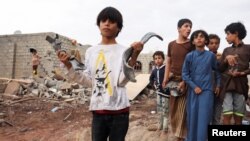 A boy holds shrapnel from a missile at the site of Houthi missile attack, in Marib, Yemen, Oct. 3, 2021.