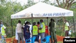 Forensic experts and homicide detectives from the Directorate of Criminal Investigations, gather to exhume bodies of starvation cult victims, in Kilifi