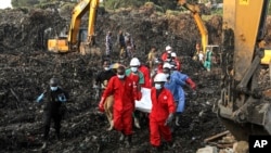 Red Cross personnel carry the body of a victim at the site of a collapsed landfill in Kampala, Uganda, Aug. 11, 2024. 