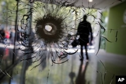 FILE - A bullet hole is pictured on a shop window of the Champs Elysees boulevard in Paris, April 21, 2017. The Islamic State group claimed responsibility for the deadly shooting.