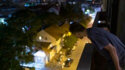In this photo taken on Friday, July 2, 2021, Nemanja Dragic, 36, looks at a bar across the street from his apartment in Belgrade, Serbia. The loud music and noise coming from bars and other nightlife places in Serbia's capital are a problem for residents across Belgrade. (AP Photo/Marko Drobnjakovic)