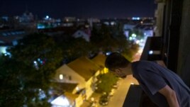 In this photo taken on Friday, July 2, 2021, Nemanja Dragic, 36, looks at a bar across the street from his apartment in Belgrade, Serbia. The loud music and noise coming from bars and other nightlife places in Serbia's capital are a problem for residents across Belgrade. (AP Photo/Marko Drobnjakovic)